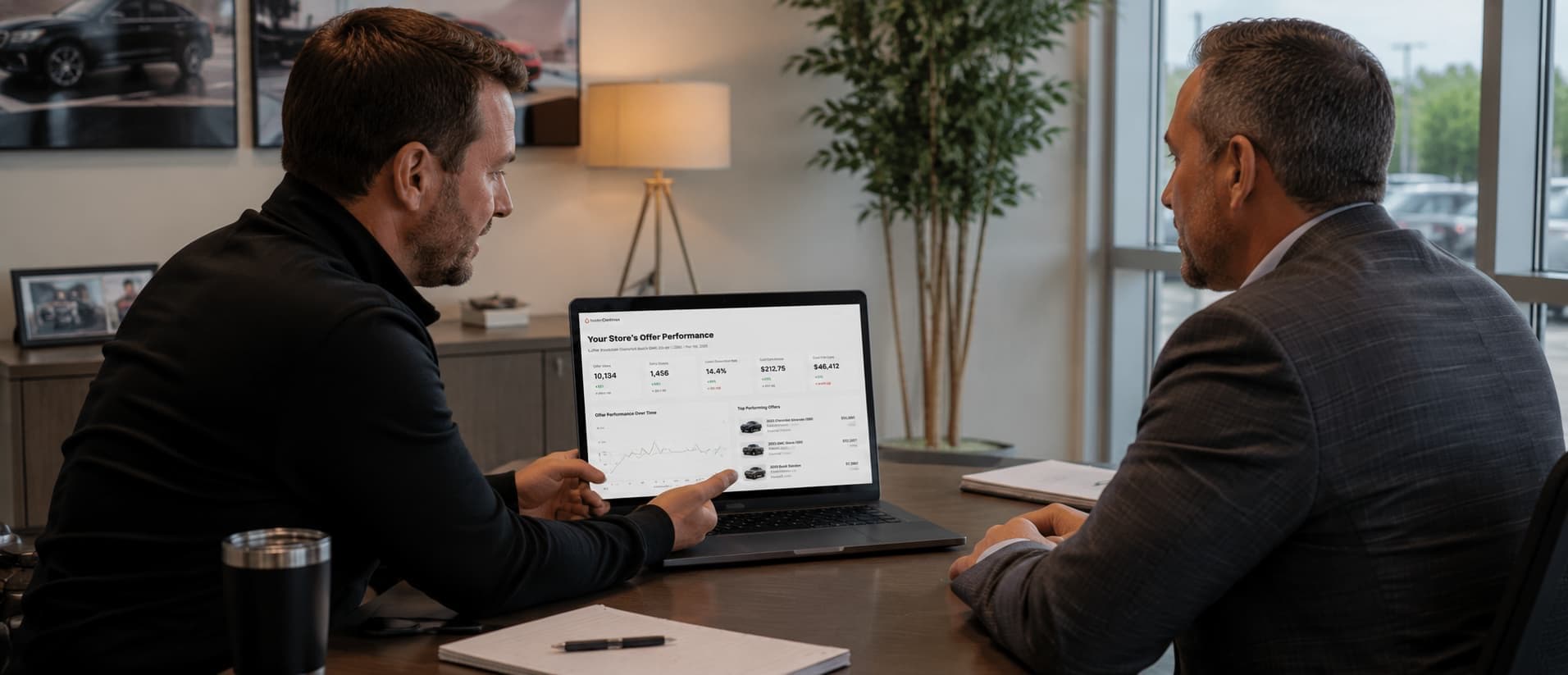 Account manager presenting offer performance reporting on a laptop to a dealer principal